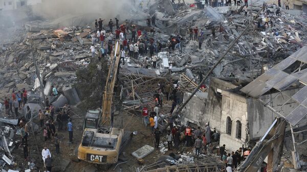 Palestinos inspeccionan los daños de los edificios destruidos tras los ataques aéreos israelíes sobre la ciudad de Gaza, el 25 de octubre, 2023 - Sputnik Mundo