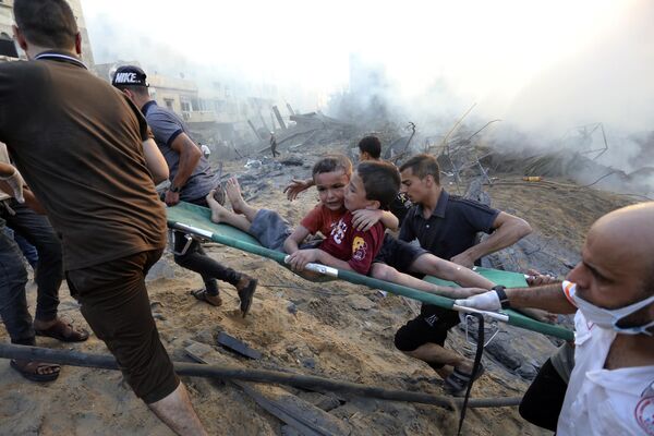 Palestinos evacuan a niños heridos tras los ataques aéreos israelíes contra la ciudad de Gaza. - Sputnik Mundo
