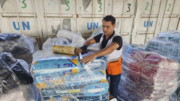 Personal de las Naciones Unidas y de la Media Luna Roja prepara la ayuda para su distribución a los palestinos en el punto de la Agencia de las ONU para refugiados  - Sputnik Mundo