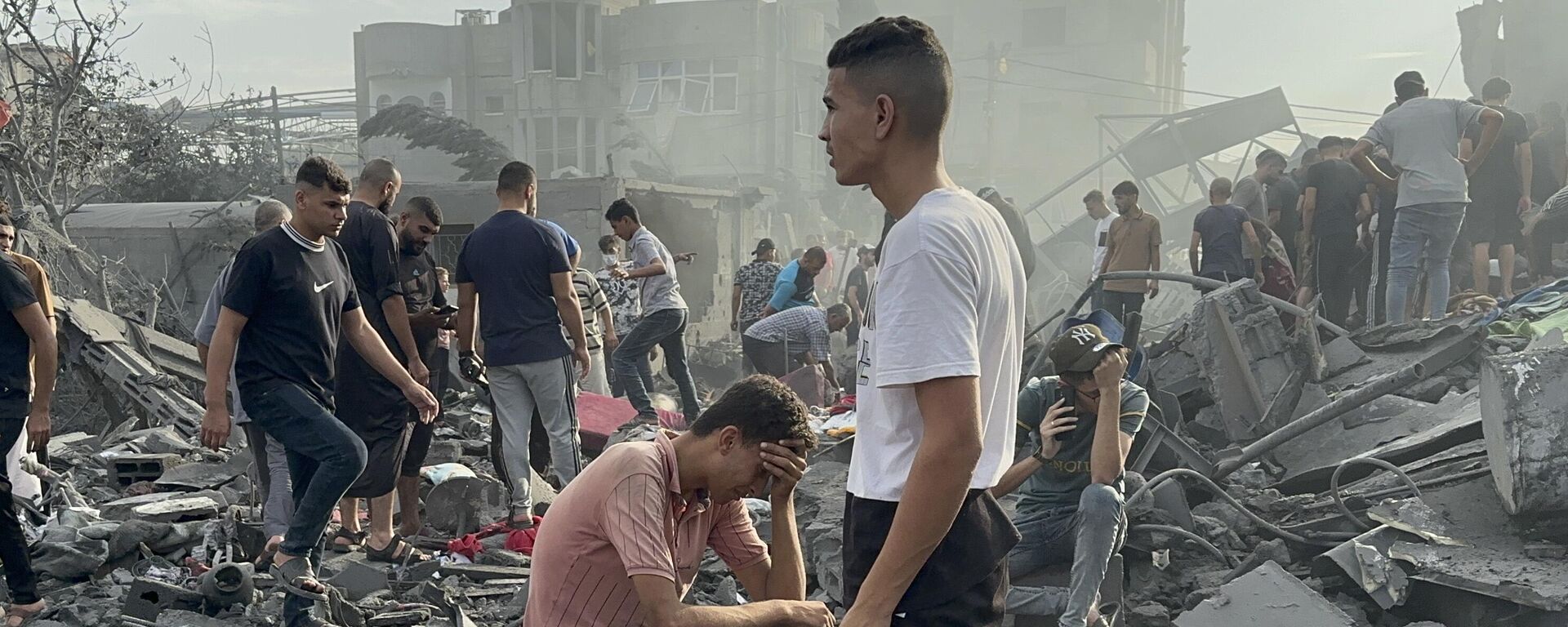 Un hombre sentado sobre escombros mientras otros deambulan entre los escombros de los edificios que fueron blanco de ataques aéreos israelíes en el campo de refugiados de Jabalia, en el norte de la Franja de Gaza - Sputnik Mundo, 1920, 03.11.2023