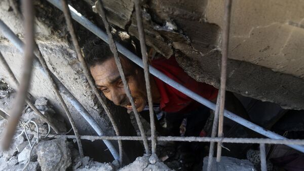 Un palestino busca sobrevivientes en los escombros tras bombardeo de Israel contra la Franja de Gaza - Sputnik Mundo