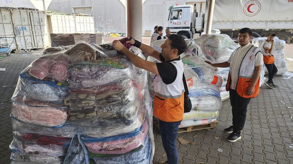 Trabajadores de las Naciones Unidas y de la Media Luna Roja preparan la ayuda para su distribución a los palestinos en el almacén del UNRWA  - Sputnik Mundo