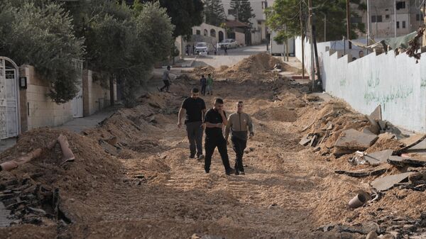 Unos palestinos caminan por una calle destruida en una incursión del Ejército israelí en Yenín, Cisjordania - Sputnik Mundo
