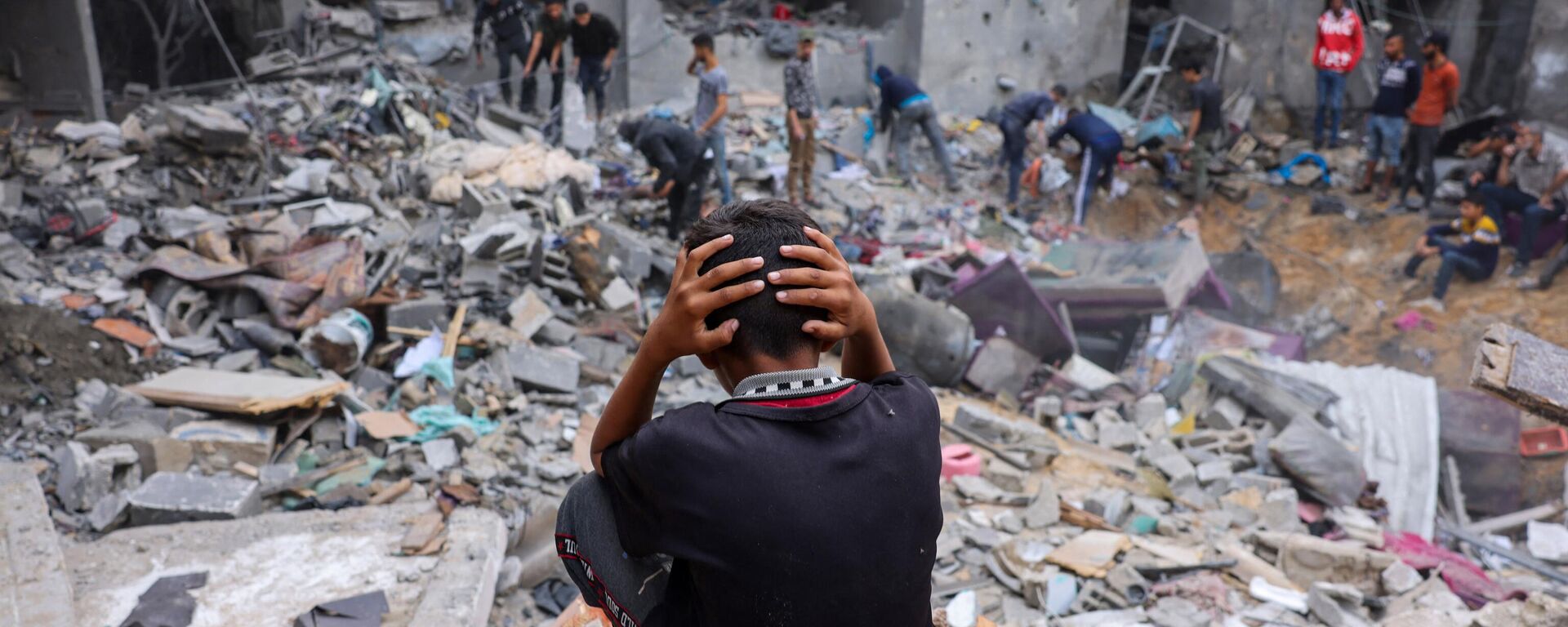 Un niño reacciona mientras la gente rescata pertenencias entre los escombros de un edificio dañado tras los ataques contra Rafah, en el sur de la Franja de Gaza, el 12 de noviembre de 2023 - Sputnik Mundo, 1920, 22.11.2023