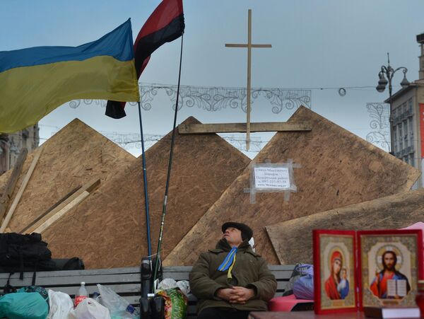 A principios de diciembre, los manifestantes instalaron un campamento en la Plaza de la Independencia, levantaron barricadas en sus entradas y acordonaron el perímetro de la plaza. En la foto: un participante del Euromaidán en las barricadas. - Sputnik Mundo