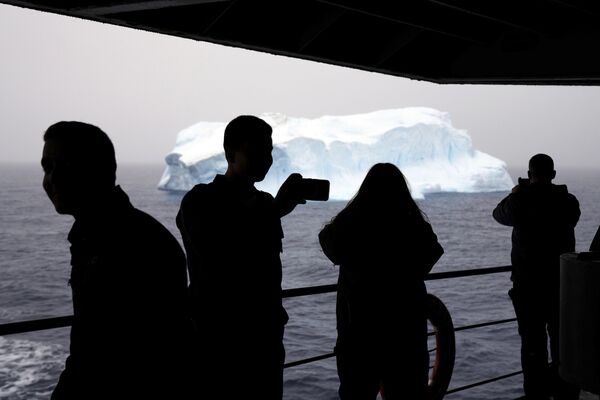 La Antártida es un continente situado en el extremo sur de la Tierra. Su centro coincide aproximadamente con el polo sur geográfico. También se denomina Antártida a la parte del mundo formada por el continente antártico y las islas que lo rodean.En la foto: pasajeros del buque Aquiles de la Armada chilena observan un iceberg en el estrecho de Bransfield, en las islas Shetland del Sur. - Sputnik Mundo