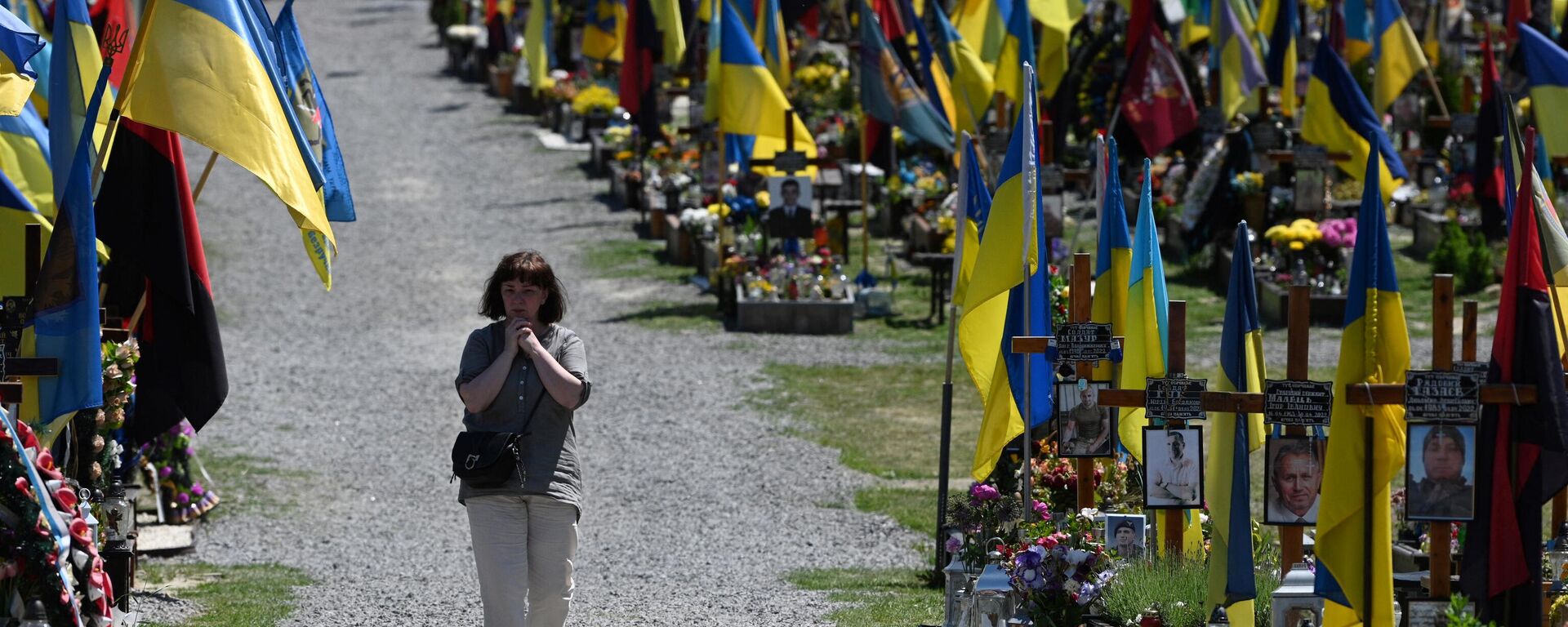 Una mujer pasa por un cementerio ucraniano - Sputnik Mundo, 1920, 28.11.2023