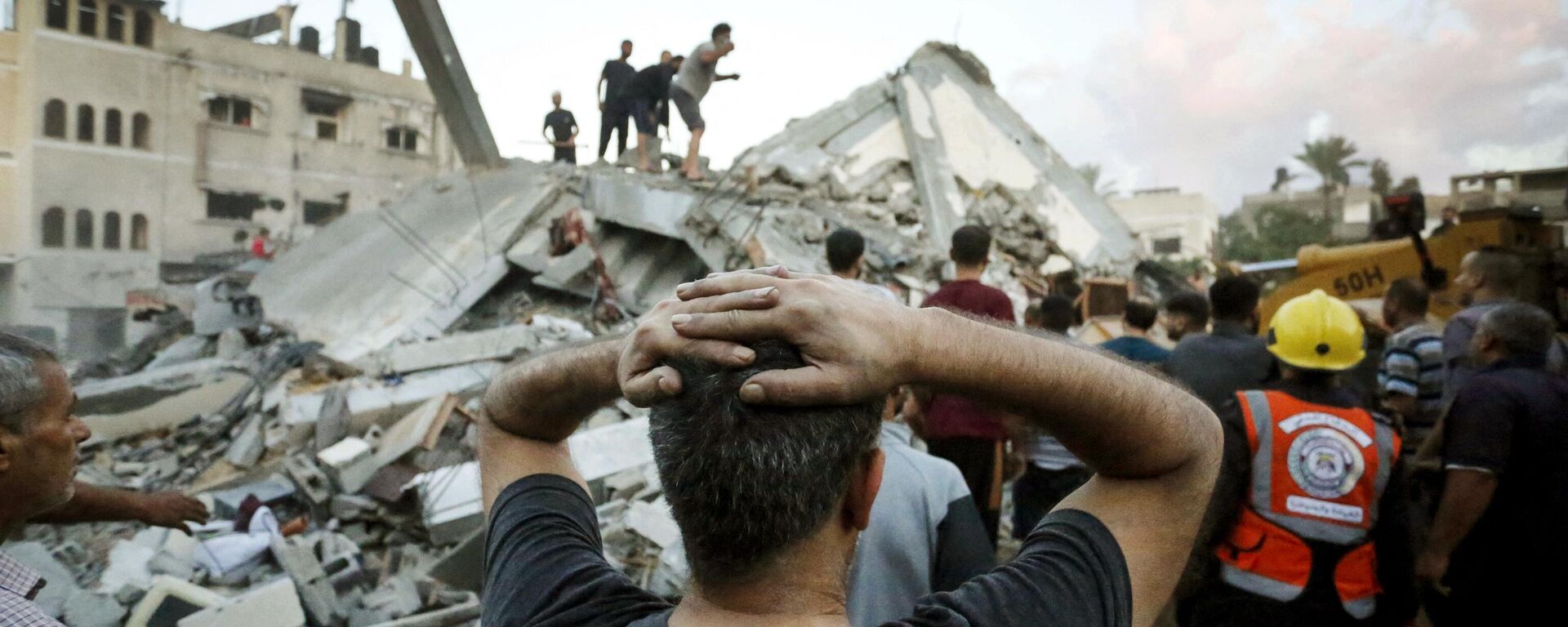 Un hombre reacciona mientras observa cómo socorristas y civiles retiran los escombros de una vivienda destruida tras un ataque israelí contra la ciudad de Deir Al Balah, en el centro de la Franja de Gaza, el 15 de octubre de 2023  - Sputnik Mundo, 1920, 07.12.2023