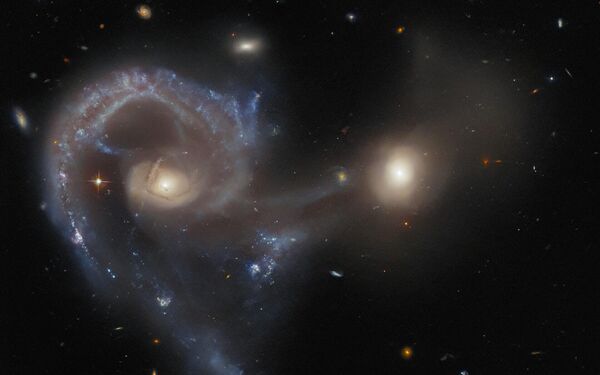 El telescopio espacial Hubble captó Arp 107, un par de galaxias en proceso de colisión entre sí. La galaxia más grande se está uniendo a la más pequeña a través de un puente de polvo y gas, y todo esto está ocurriendo a una distancia de 465 millones de años luz de la Tierra. - Sputnik Mundo
