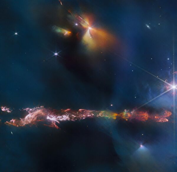 El Herbig Haro 797 (HH 797), un objeto situado a unos 1.000 años luz de la Tierra, aparece en la parte inferior de esta imagen tomada por el telescopio espacial James Webb. Los objetos Herbig Haro son zonas luminosas que rodean a estrellas recién nacidas. Los científicos creen que los brillantes objetos infrarrojos de la parte superior de la imagen contienen otras dos protoestrellas. - Sputnik Mundo