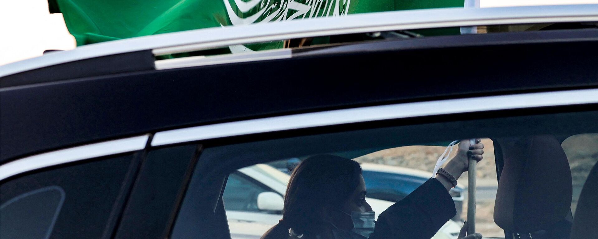 Una mujer sostiene una bandera nacional de Arabia Saudita desde la ventana de un vehículo mientras asiste a un espectáculo aéreo que marca las celebraciones del 93.º Día Nacional de Arabia Saudí en Riad el 23 de septiembre de 2023.  - Sputnik Mundo, 1920, 23.12.2023