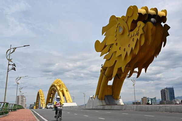Una mujer monta en bicicleta en el Puente del Dragón en la ciudad de Danang, Vietnam. - Sputnik Mundo