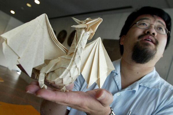 El artista profesional canadiense de origami, Joseph Wu, con su obra favorita, un dragón de papel plegado. - Sputnik Mundo