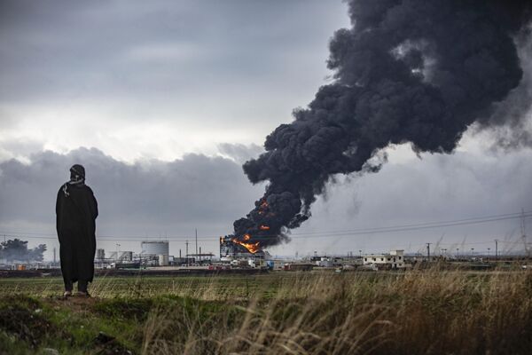 Un espeso humo se eleva desde un incendio en un tanque de almacenamiento de petróleo en el campo petrolífero de Al Rawda, cerca de al Qahtaniya, en el noreste de Siria, tras los ataques aéreos turcos contra instalaciones del Partido de los Trabajadores del Kurdistán. - Sputnik Mundo