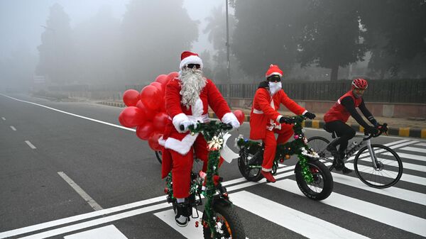 Personas disfrazadas de Papá Noel conducen por la calle en Nueva Delhi en el día de Navidad - Sputnik Mundo