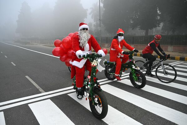Ciclistas disfrazados de Papá Noel en una calle de Nueva Delhi, India. - Sputnik Mundo