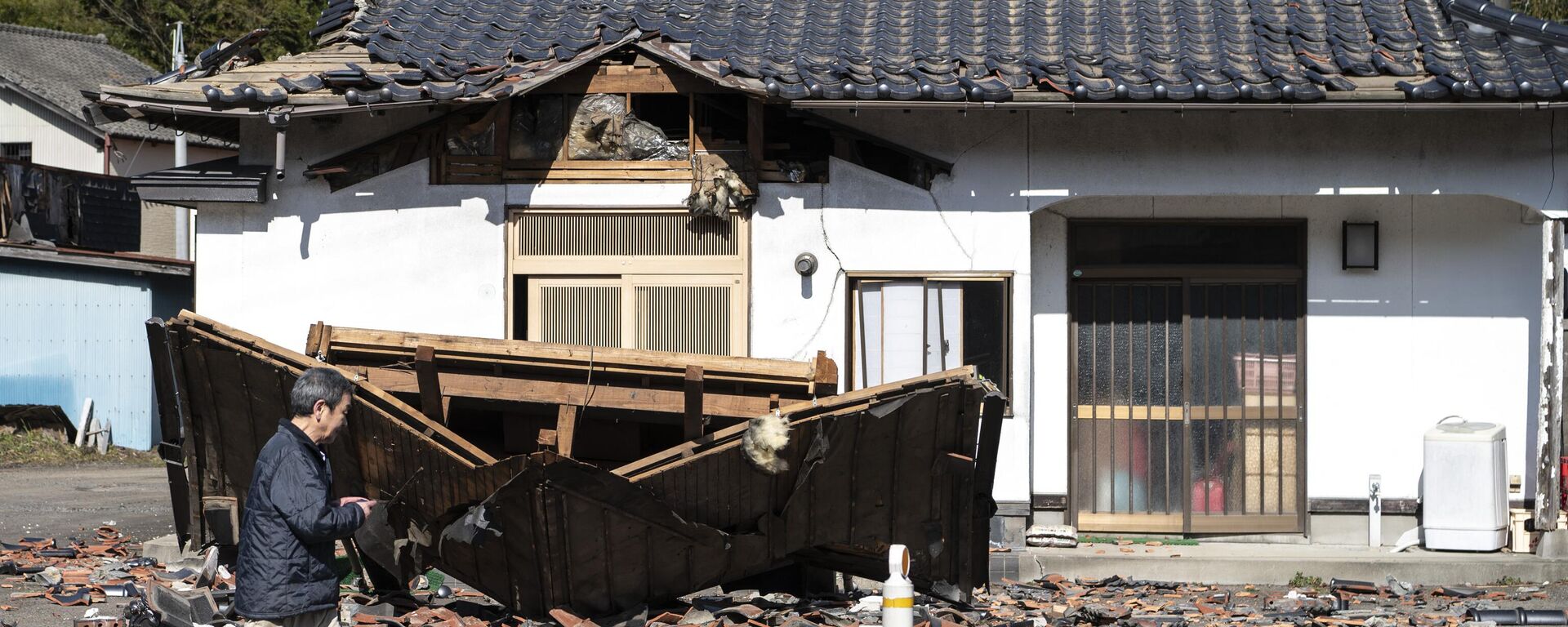 Hombre camina delante de su restaurante dañado en Shiroishi, prefectura de Miyagi, el 17 de marzo de 2022, después de que un terremoto de magnitud 7,3 sacudiera el este de Japón la noche anterior - Sputnik Mundo, 1920, 03.01.2024