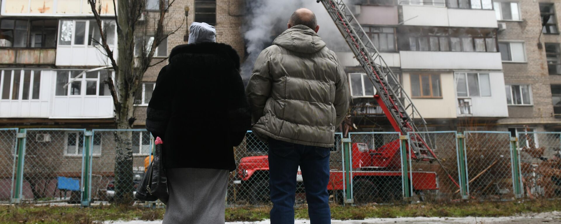 Personas observan cómo bomberos extinguen un incendio en un edificio residencial de Donetsk, provocado por bombardeos de Ucrania - Sputnik Mundo, 1920, 21.01.2024