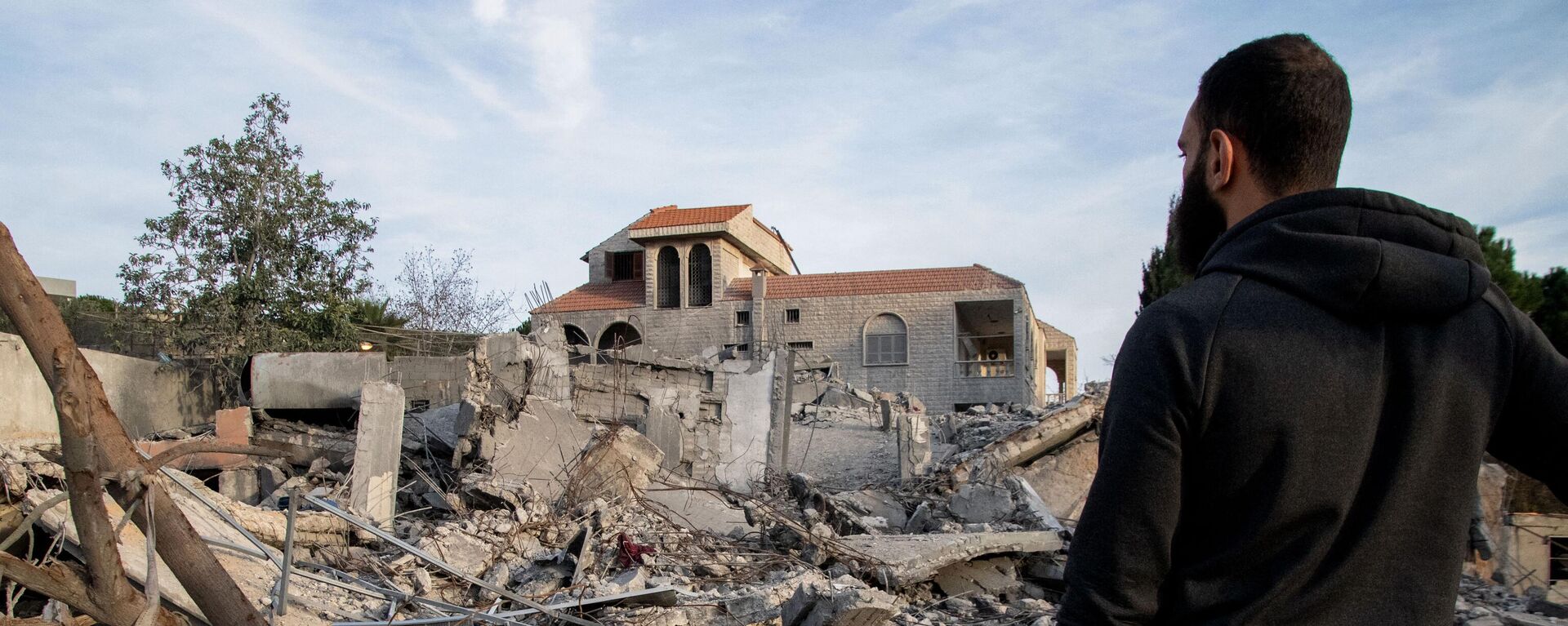 Un hombre observando un edificio destruido el 8 de enero de 2024 tras un ataque aéreo israelí en la aldea de Kfar Kila, en el sur del Líbano - Sputnik Mundo, 1920, 15.01.2024