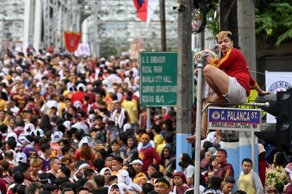 Un devoto católico sube a una señal de tráfico durante la procesión religiosa anual celebrada en honor del llamado Nazareno Negro en Manila, Filipinas. - Sputnik Mundo