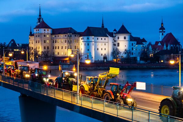 Agricultores pasando con sus tractores por delante del castillo de Hartenfels y cruzando el río Elba en Torgau, Alemania, durante una protesta contra los planes del Gobierno de suprimir las ayudas a los granjeros. - Sputnik Mundo