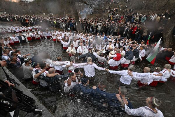 Cristianos ortodoxos bailando la danza tradicional Horo en el río Tundzha en Kalofer, Bulgaria, como parte de las celebraciones de la Epifanía. - Sputnik Mundo
