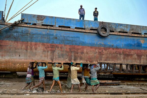 Trabajadores transportando una plancha de metal para reparar un viejo barco en un astillero a orillas del río Buriganga en Daka, Bangladesh. - Sputnik Mundo