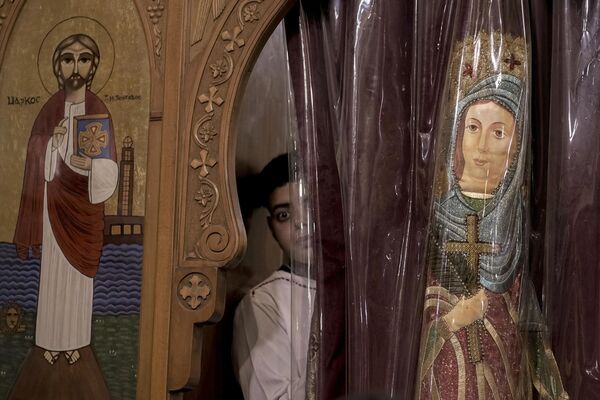 Un fiel de la Iglesia ortodoxa copta mira por una ventana durante un servicio de Nochebuena en la Iglesia de Ava Bishoy y San Karas Anba de Anchorite en El Cairo, Egipto. - Sputnik Mundo