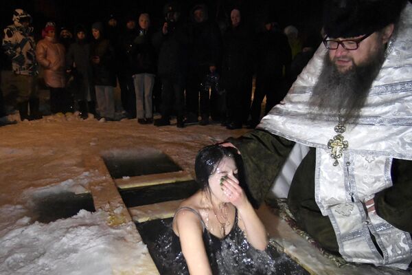 El agua de la Epifanía se llama agua bendita y se considera una reliquia sagrada capaz de curar el alma y el cuerpo. Foto: Baño bautismal en la aldea de Bolshaya Murta, en la región de Krasnoyarsk. - Sputnik Mundo