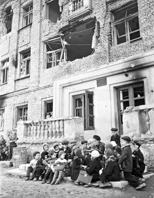 Durante los largos meses del bloqueo, los fascistas lanzaron sobre Leningrado 150.000 proyectiles de artillería pesada y más de 107.000 bombas incendiarias y de alto poder explosivo. Destruyeron 3.000 edificios y dañaron más de 7.000.En la foto: una clase en el porche de una escuela arrasada en Leningrado. - Sputnik Mundo