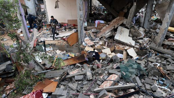 Un joven palestino rescata algunos objetos en medio de las ruinas de un edificio destruido por Israel - Sputnik Mundo