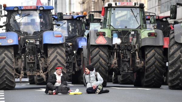 Agricultores con sus tractores se sientan en la calle mientras bloquean el tráfico en una carretera que conduce al centro de Bruselas, durante una manifestación, el 3 de marzo de 2023 - Sputnik Mundo