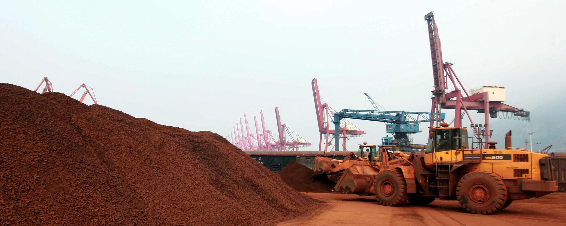 En una imagen tomada el 5 de septiembre de 2010, un hombre que conduce una pala cargadora desplaza tierra que contiene minerales de tierras raras para cargarla en un puerto de Lianyungang, provincia oriental china de Jiangsu. - Sputnik Mundo, 1920, 04.02.2024