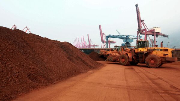En una imagen tomada el 5 de septiembre de 2010, un hombre que conduce una pala cargadora desplaza tierra que contiene minerales de tierras raras para cargarla en un puerto de Lianyungang, provincia oriental china de Jiangsu. - Sputnik Mundo