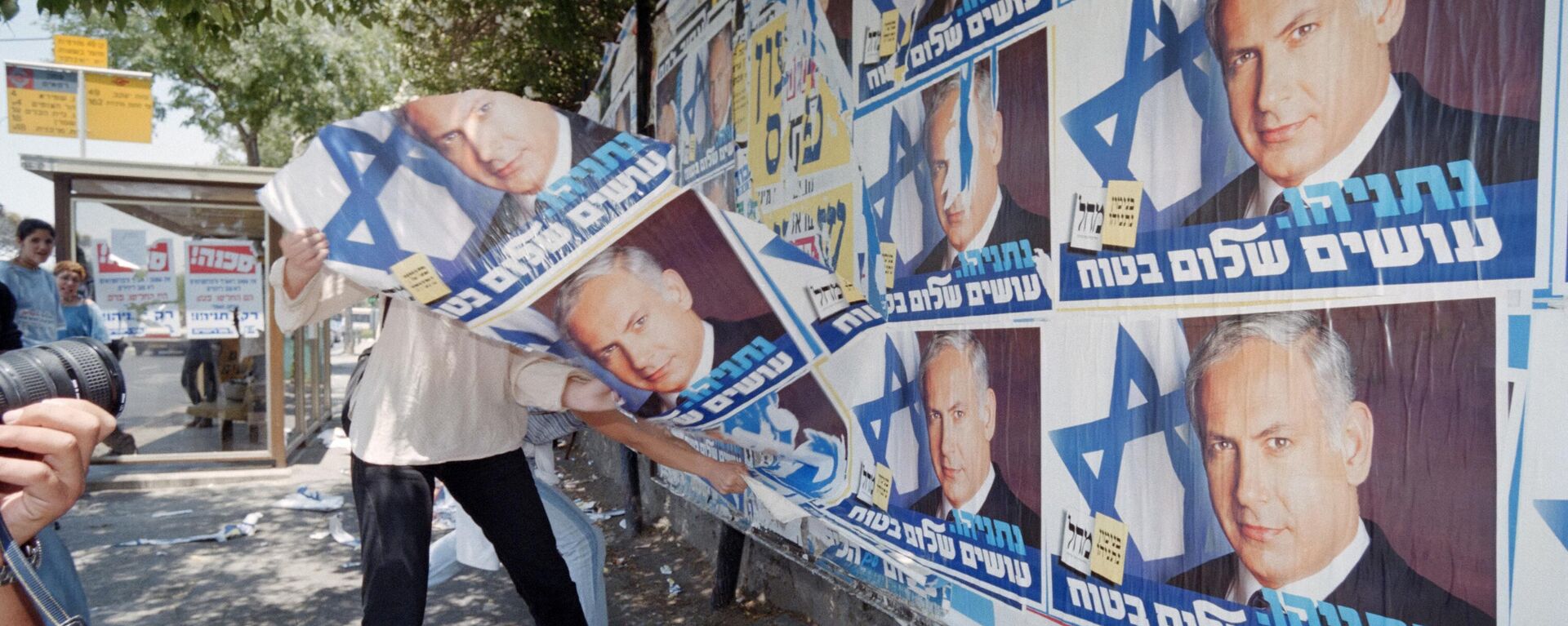 Una persona inconforme retira propaganda del primer ministro israelí Benjamín Netanyahu en Jerusalén - Sputnik Mundo, 1920, 22.02.2024