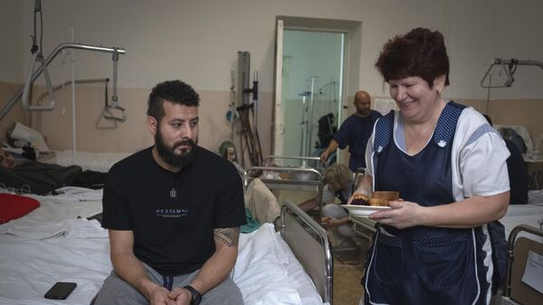 Una enfermera lleva el almuerzo a un soldado con apodo 'Checho' de Medellín, Colombia, en un hospital de Ucrania, el miércoles 20 de diciembre de 2023 - Sputnik Mundo