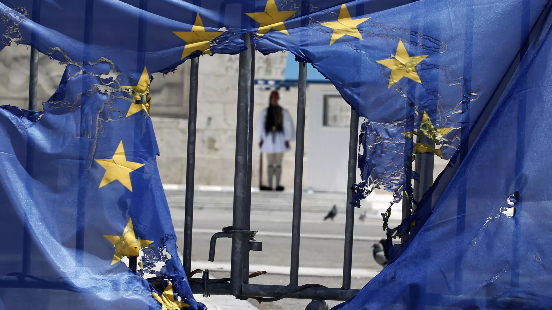 Un guardia presidencial griego permanece enmarcado por los restos de una bandera de la Unión Europea, medio quemada por manifestantes en Atenas, el 1 de mayo de 2013 - Sputnik Mundo, 1920, 17.07.2024