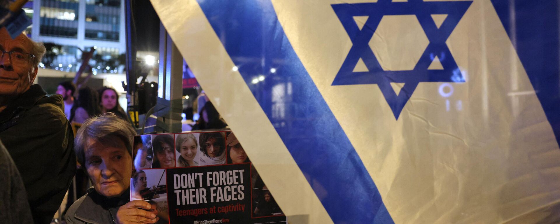 Una mujer sostiene una pancarta con imágenes de los rehenes israelíes retenidos en Gaza desde los ataques del 7 de octubre por militantes palestinos de Hamás, mientras familiares y simpatizantes marchan durante una manifestación que pide su liberación en Tel Aviv, el 15 de febrero de 2024. - Sputnik Mundo, 1920, 15.02.2024