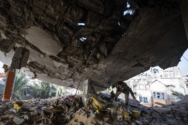 Un palestino recoge objetos de una casa destruida por un ataque israelí en Rafah, Franja de Gaza. - Sputnik Mundo