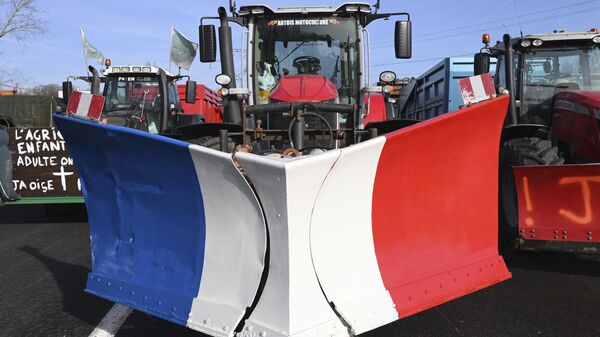 Tractores, el del centro con los colores de la bandera francesa, bloquean una carretera el 29 de enero de 2024 al norte de París - Sputnik Mundo