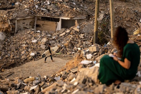 Un surfista pasa junto a los escombros de las casas de la ciudad de Imsouane, demolidas en el marco de un plan de destrucción de construcciones ilegales en la costa marroquí. - Sputnik Mundo