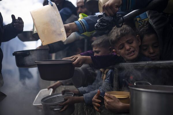Palestinos hacen cola para recibir comida gratuita en la ciudad de Rafah, en el sur de la Franja de Gaza. - Sputnik Mundo