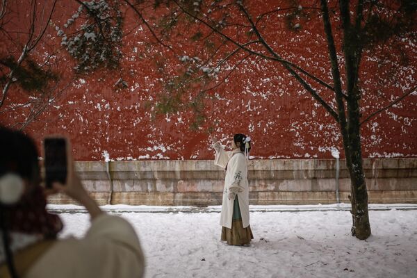 Una mujer con traje tradicional posa para una foto un día después de una nevada en Pekín, China. - Sputnik Mundo