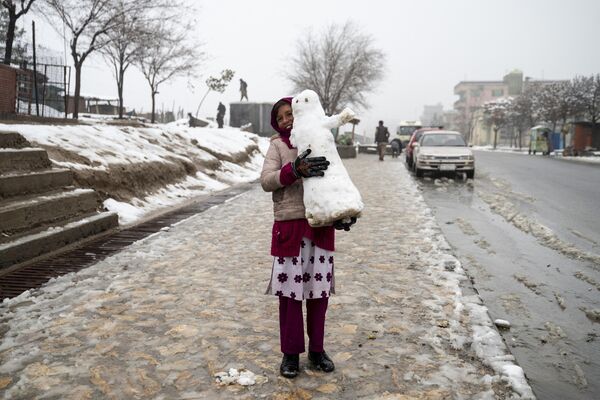 Una niña con un muñeco de nieve en una calle de Kabul, Afganistán. - Sputnik Mundo