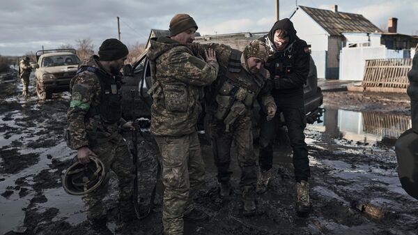 Soldados ucranianos ayudan a un compañero herido a subir a un vehículo de evacuación en la línea del frente en la región de Donetsk, el 20 de febrero de 2023 - Sputnik Mundo