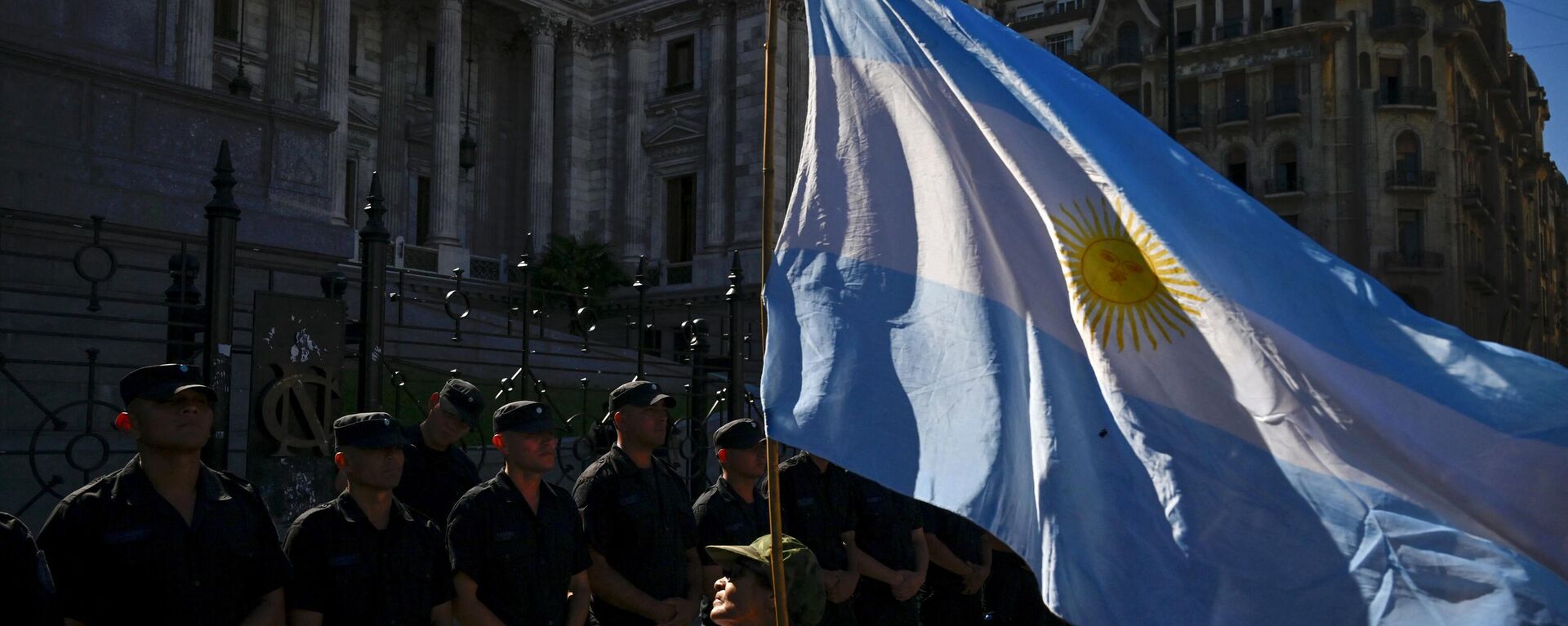 Una mujer sostiene una bandera argentina frente a una línea de policías durante una huelga nacional contra el Gobierno de Javier Milei en Buenos Aires el 24 de enero de 2024 - Sputnik Mundo, 1920, 13.06.2024