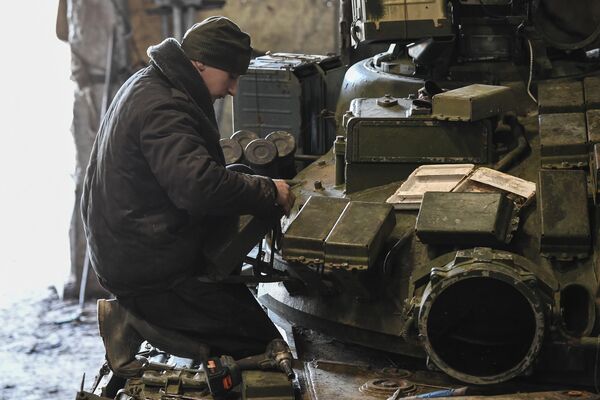 Un soldado está arreglando los bloques de protección dinámica de un tanque. - Sputnik Mundo