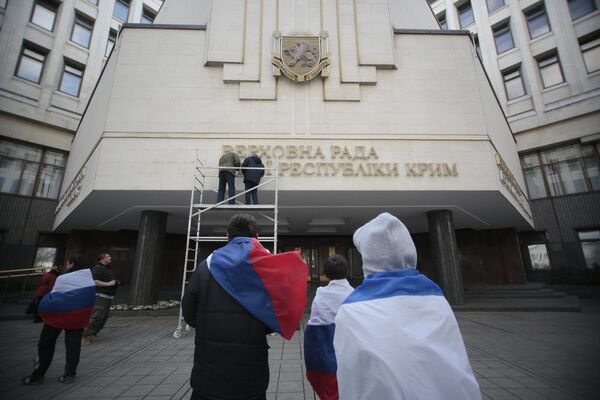 La situación cambiaba rápidamente. En la foto: trabajadores retiran las letras en ucraniano del edificio del Consejo Supremo de Crimea. - Sputnik Mundo