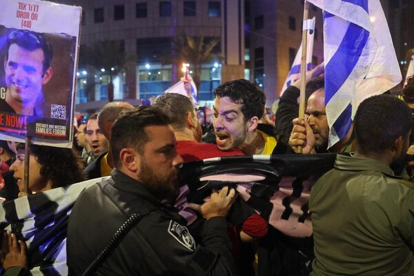 Manifestantes gritan consignas mientras las fuerzas de seguridad israelíes montan guardia durante una manifestación antigubernamental en la ciudad de Tel Aviv, en medio del actual conflicto en la Franja de Gaza. - Sputnik Mundo
