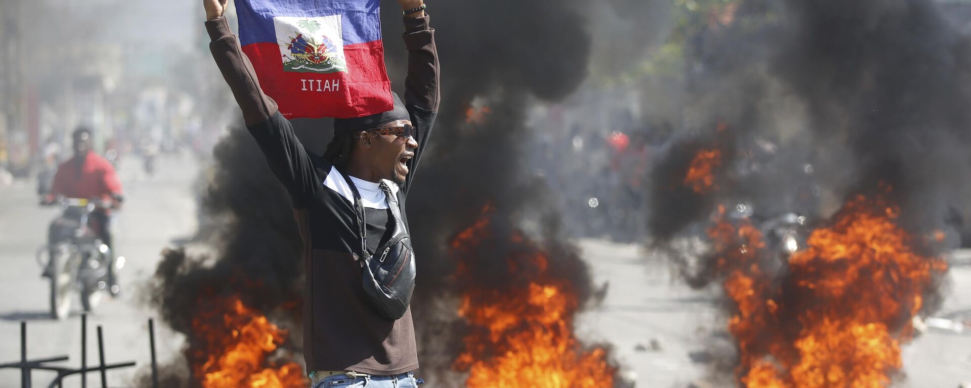 Un manifestante sostiene una bandera haitiana durante las protestas que exigen la dimisión del primer ministro Ariel Henry en Puerto Príncipe, Haití, el 1 de marzo de 2024 - Sputnik Mundo, 1920, 04.03.2024